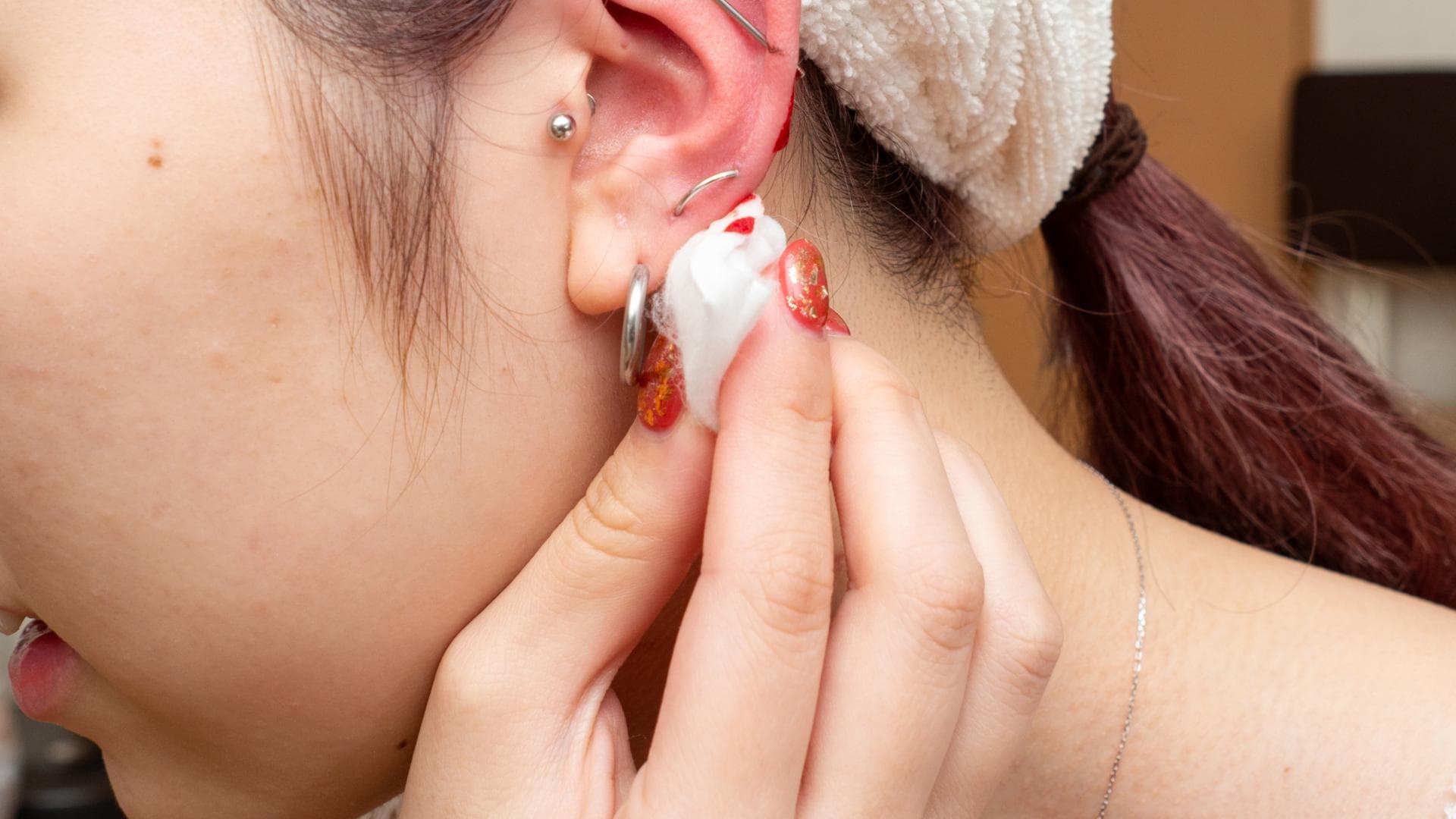 Ohrloch blutet: Diese Tipps und Hausmittel helfen Ohrloch blutet: Frau tupft sich Blut vom Ohrloch