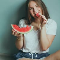 Obst und Gemüse ist für Vegetarier genau das Richtige! Mädchen isst Wassermelonet, denn sie ist Vegetarier