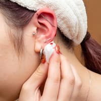 Ohrloch blutet: Diese Tipps und Hausmittel helfen Ohrloch blutet: Frau tupft sich Blut vom Ohrloch