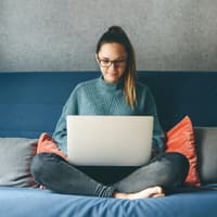 Bewerbung Nebenjob Junge Frau sitzt auf dem Sofa mit Laptop